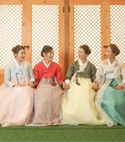 한복을 입고 나란히 앉아 웃는 네 사람